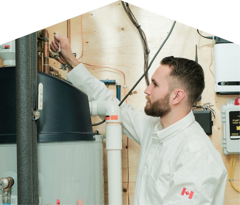 Furnasman water heater specialist adjusts piping on a large residential unit during a repair service, with exposed wood paneling and mounted utility components in the background.