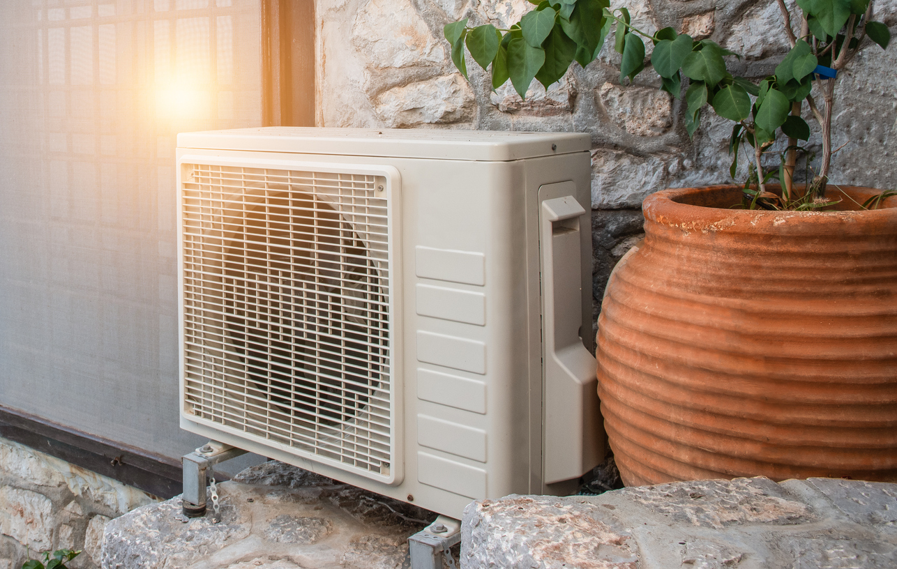Air heat pump outdoor unit against wall of Greek house. Air heat pump outdoor unit against wall of Greek house.
