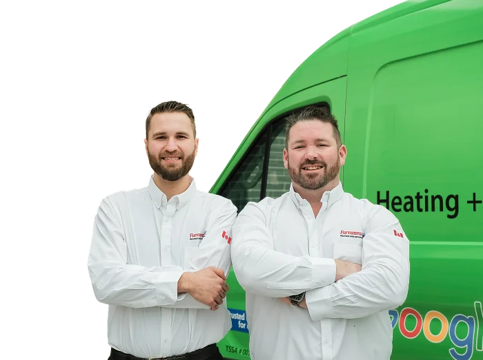 Two Furnasman technicians smiling in front of their green service van, wearing issued jackets during an on-site consultation.