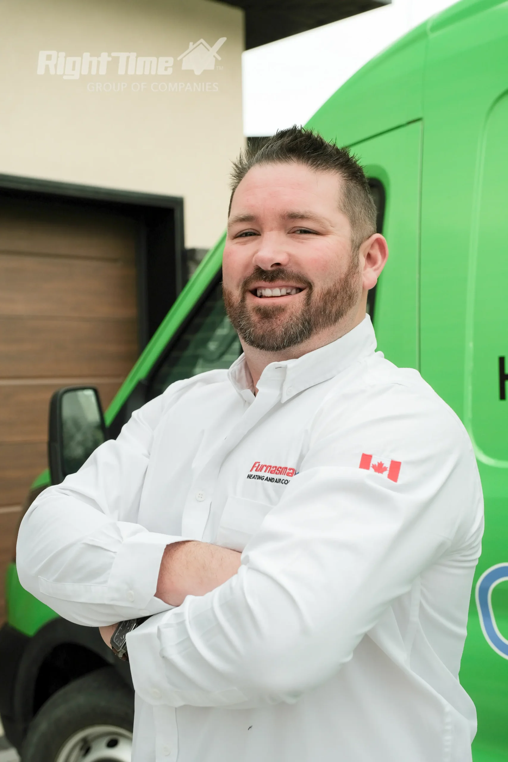 HVAC technician in a white Furnasman uniform standing with arms crossed in front of a green service van.